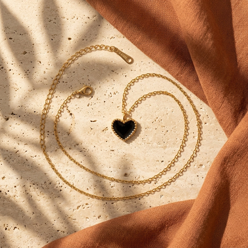 Black enamel heart pendant necklace styled flat lay, ideal for gifting