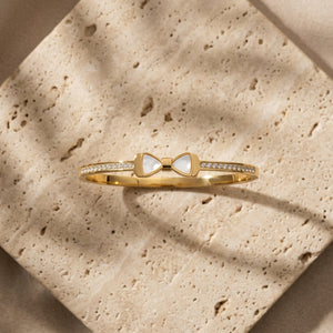 Pearl Bow Zircon Handcuff — gold-tone bangle with mother-of-pearl bow