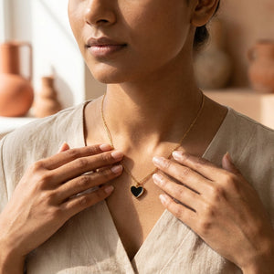 Woman holding Black Enamel Heart Necklace pendant with both hands